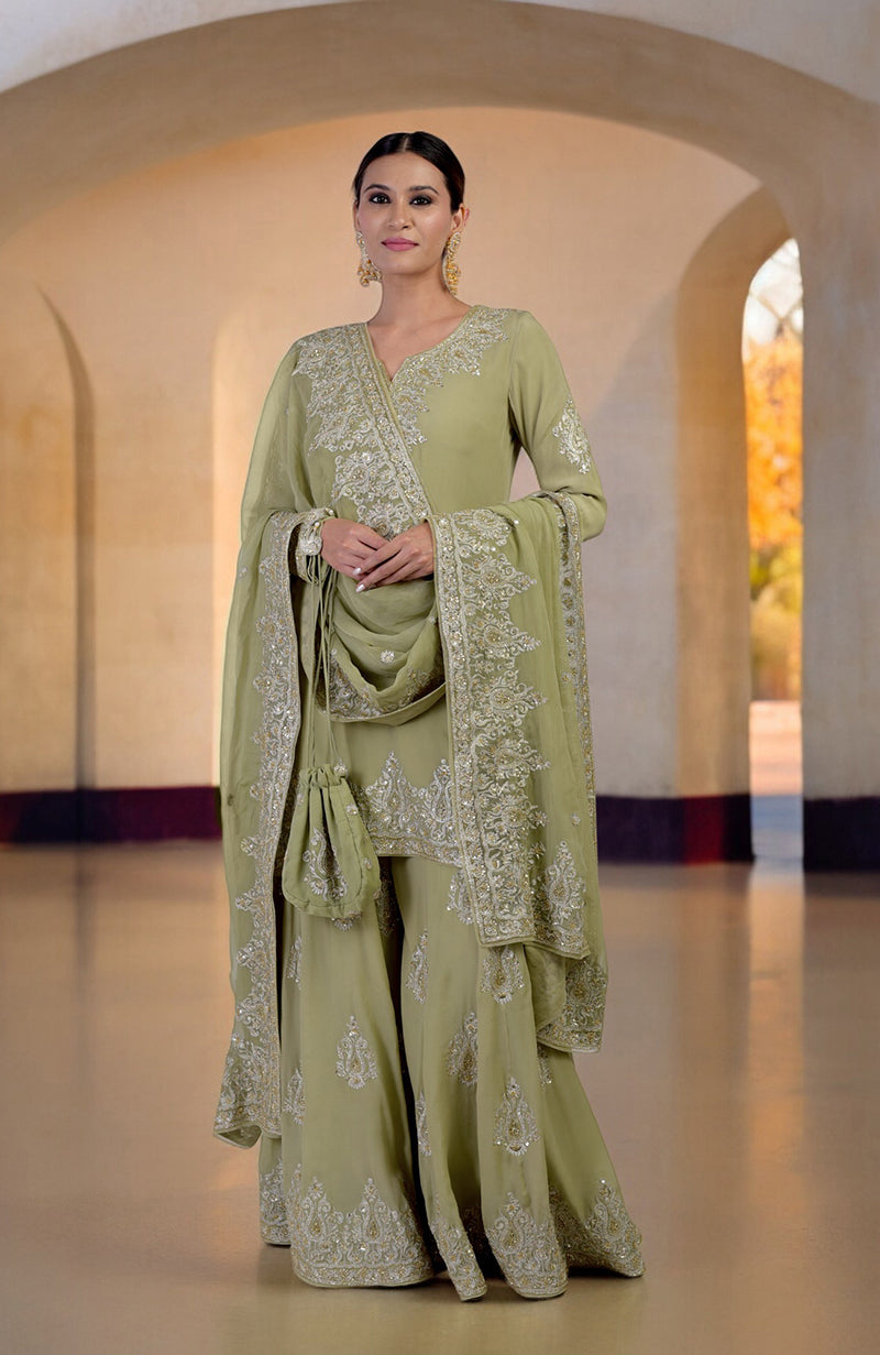 A woman models a bog green sharara set with gold Kashmiri tilla and zardozi embroidery.