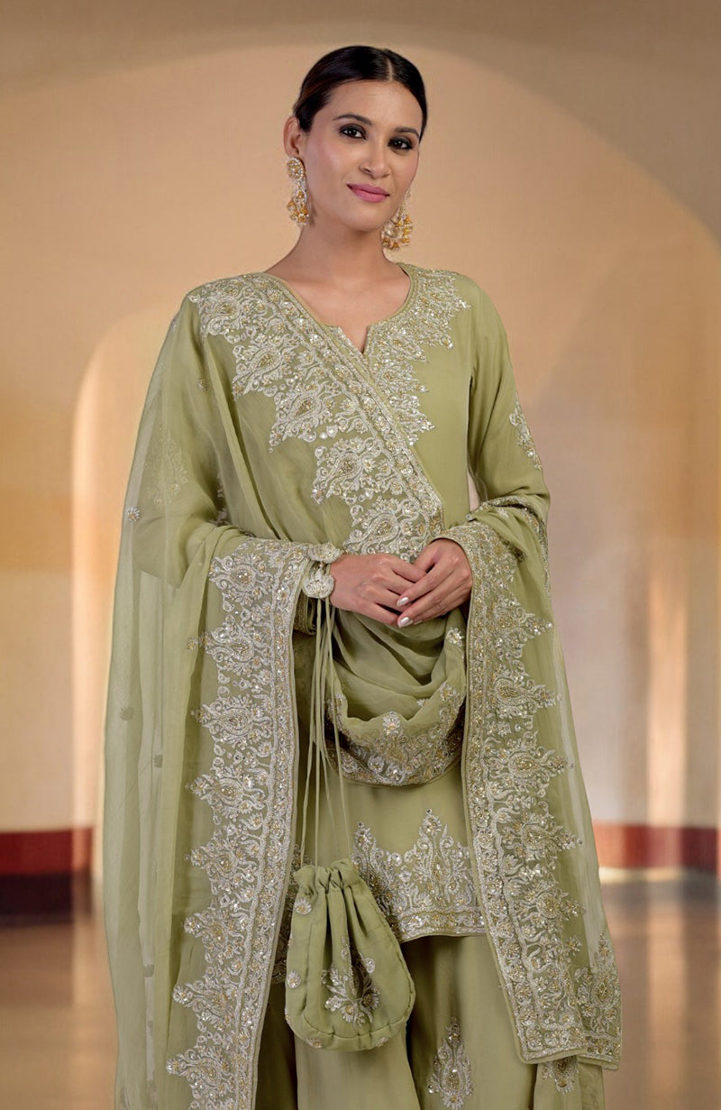 A woman models a bog green sharara set with gold Kashmiri tilla and zardozi embroidery.