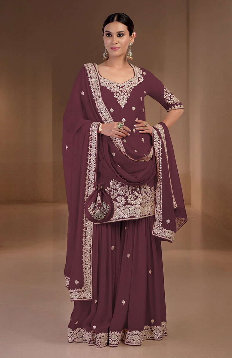 A woman models a maroon sharara set with gold embroidery and a matching potli bag.