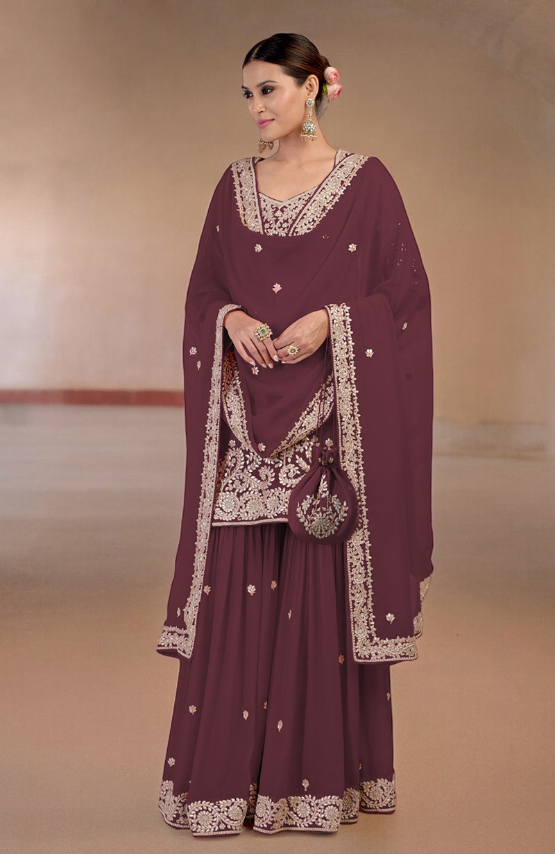 Burgundy sharara set with intricate gold embroidery and a matching potli bag.