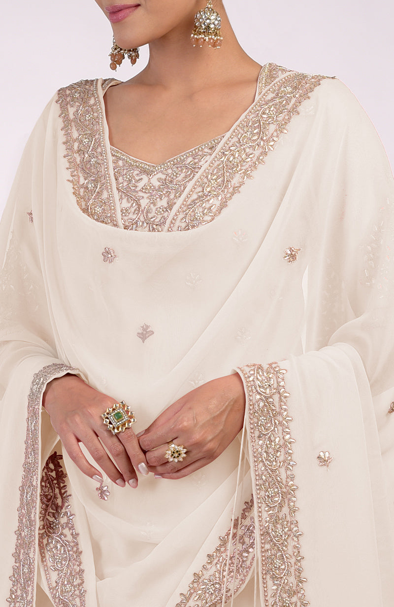 A woman models a sea salt-colored sharara set with intricate embroidery and jewelry.