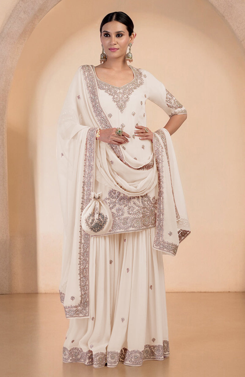 A woman models a sea salt sharara set with intricate embroidery and a matching potli bag.