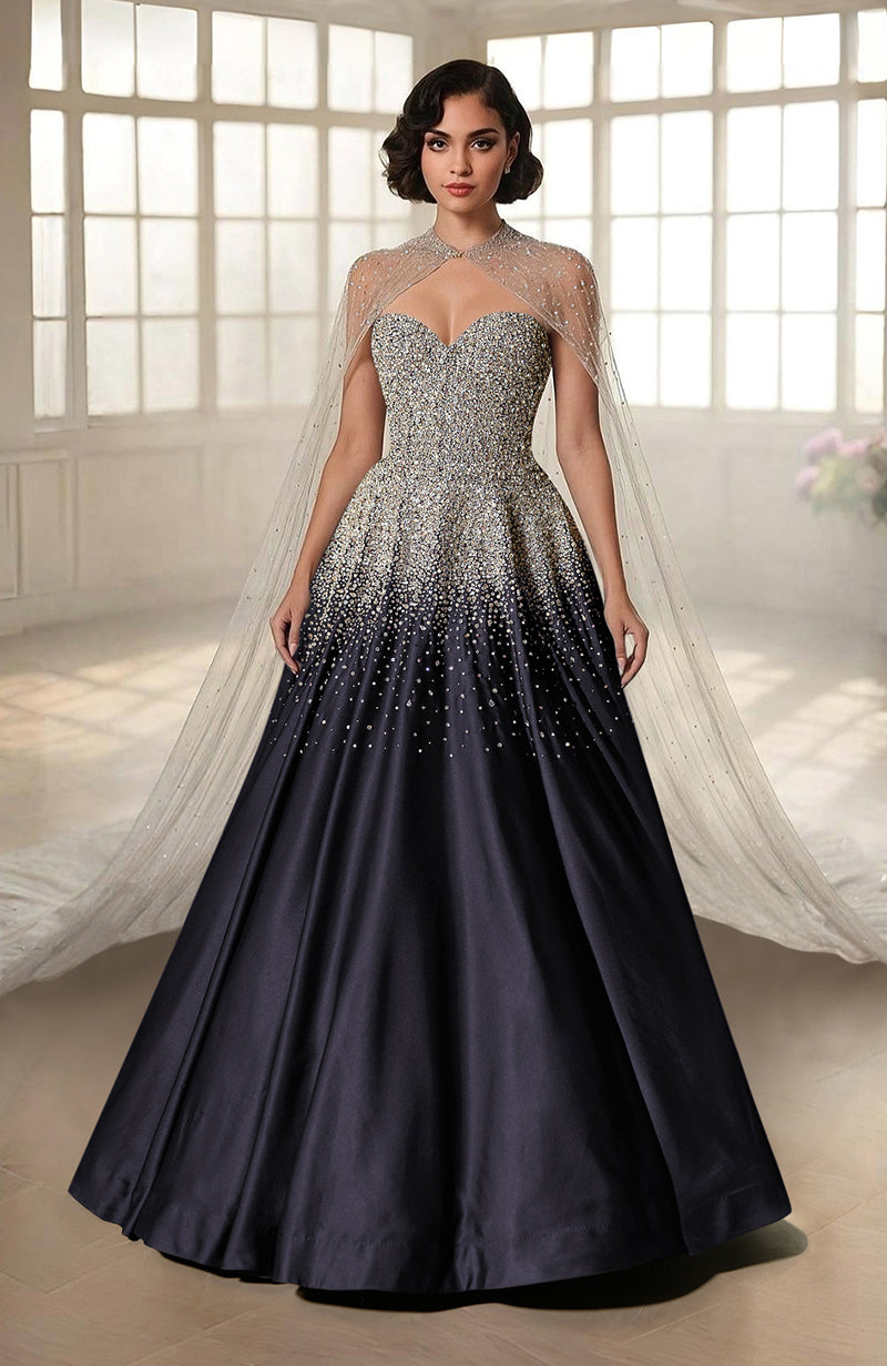 A woman models a black and silver crystal-embroidered princess gown with a sheer cape.