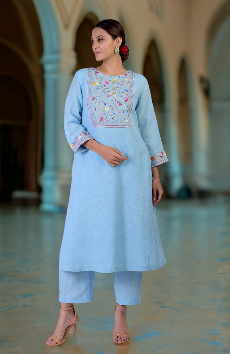A woman models a cerulean blue Parsi Gara embroidered linen kurta set.