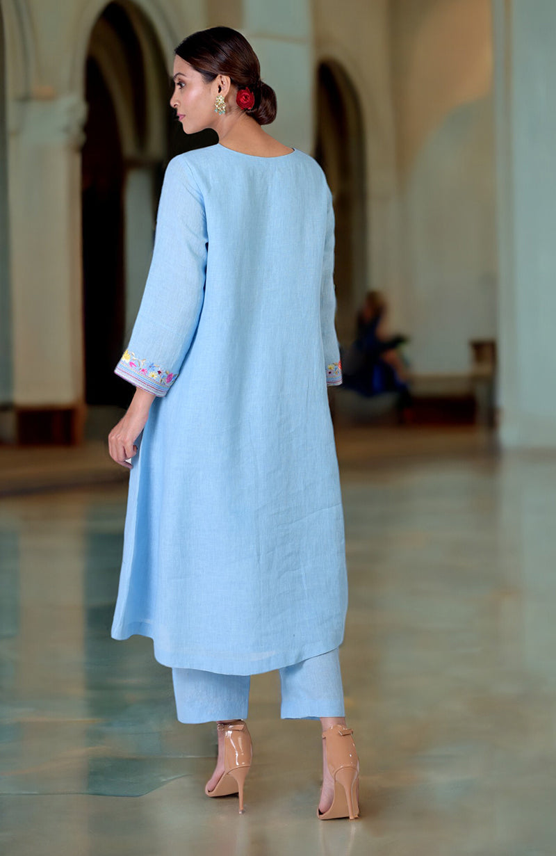 A woman from behind wears a cerulean blue linen kurta set with Parsi Gara embroidery.