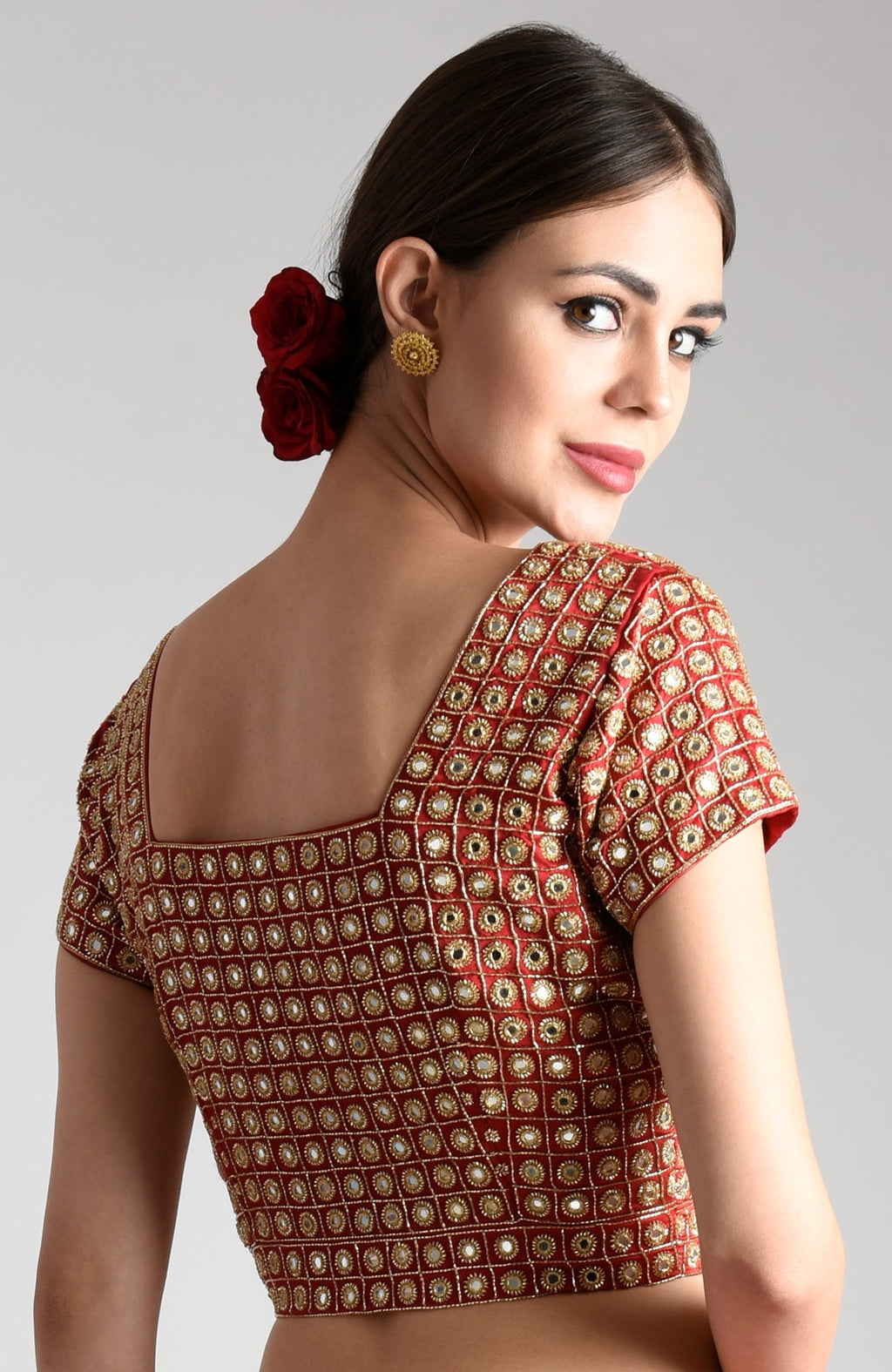 A woman models a red blouse with mirror and zardozi embroidery.