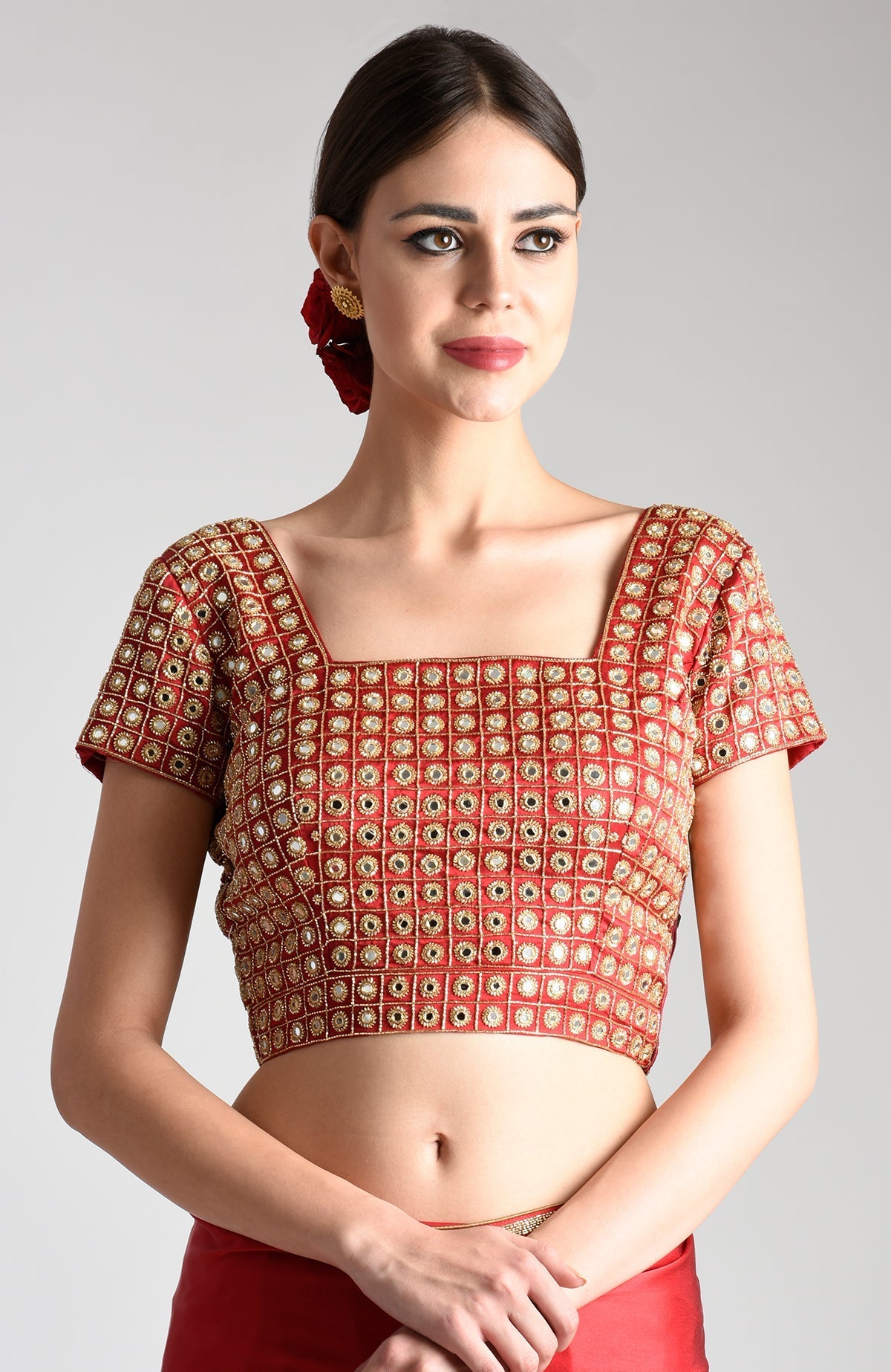 A woman models a red mirror work and zardozi hand-embroidered blouse.