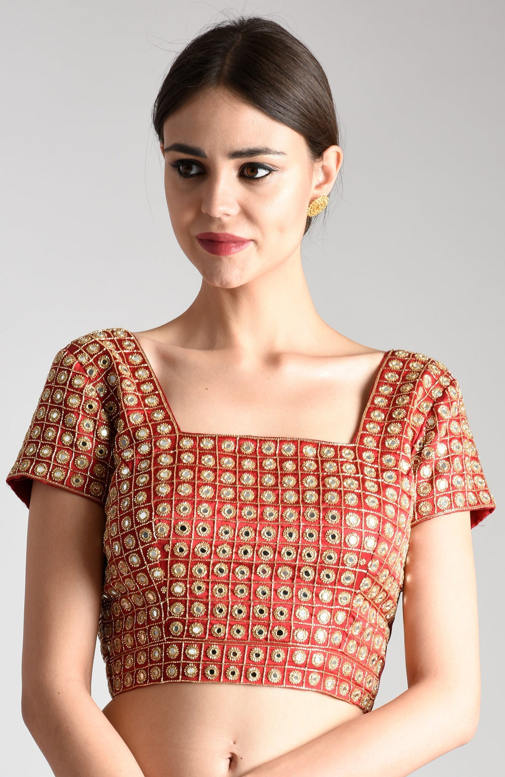 A woman models a red mirror work and zardozi hand embroidered blouse.
