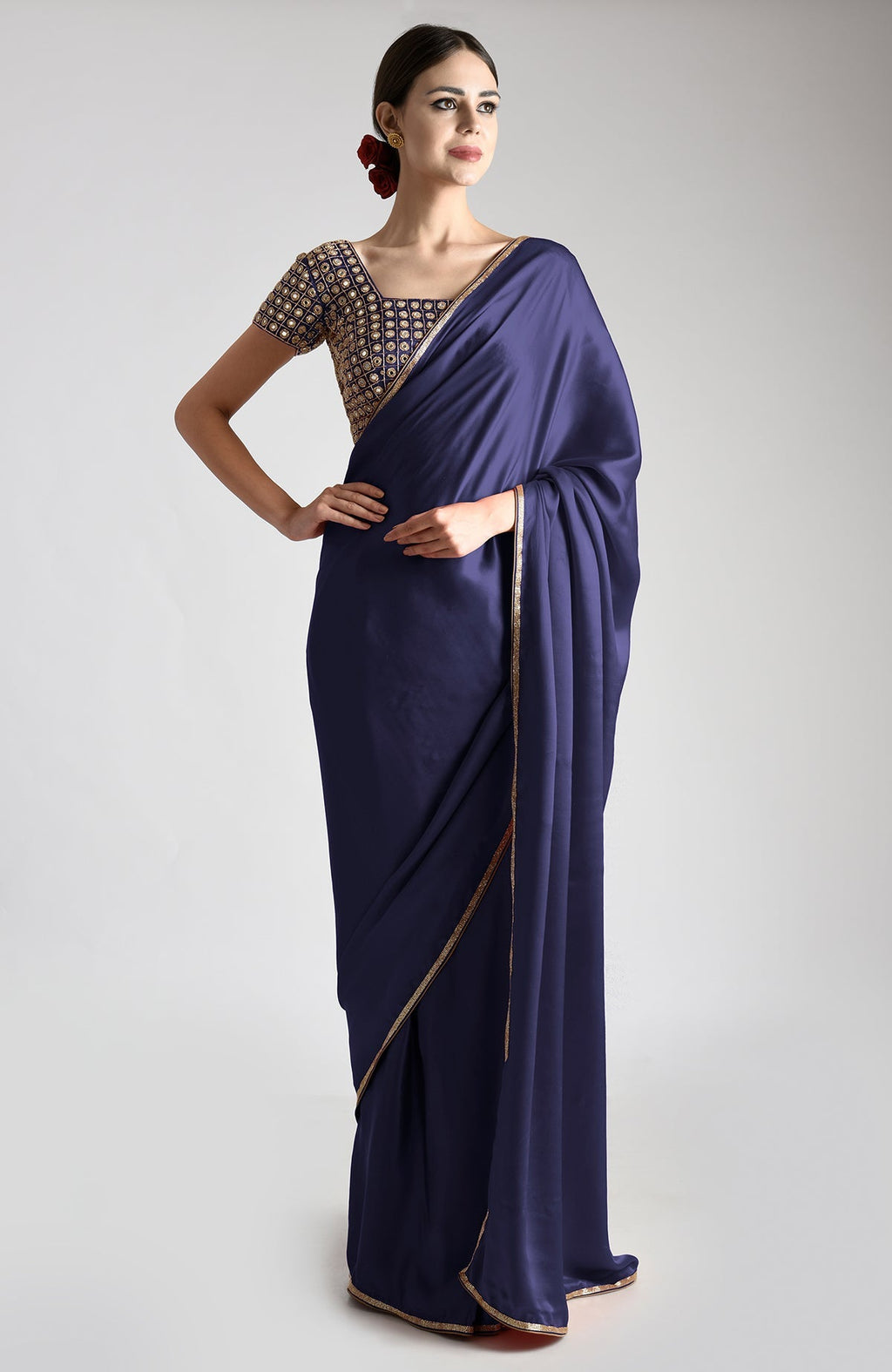A woman models a midnight blue satin silk saree with gold mirror and zardozi embroidery.