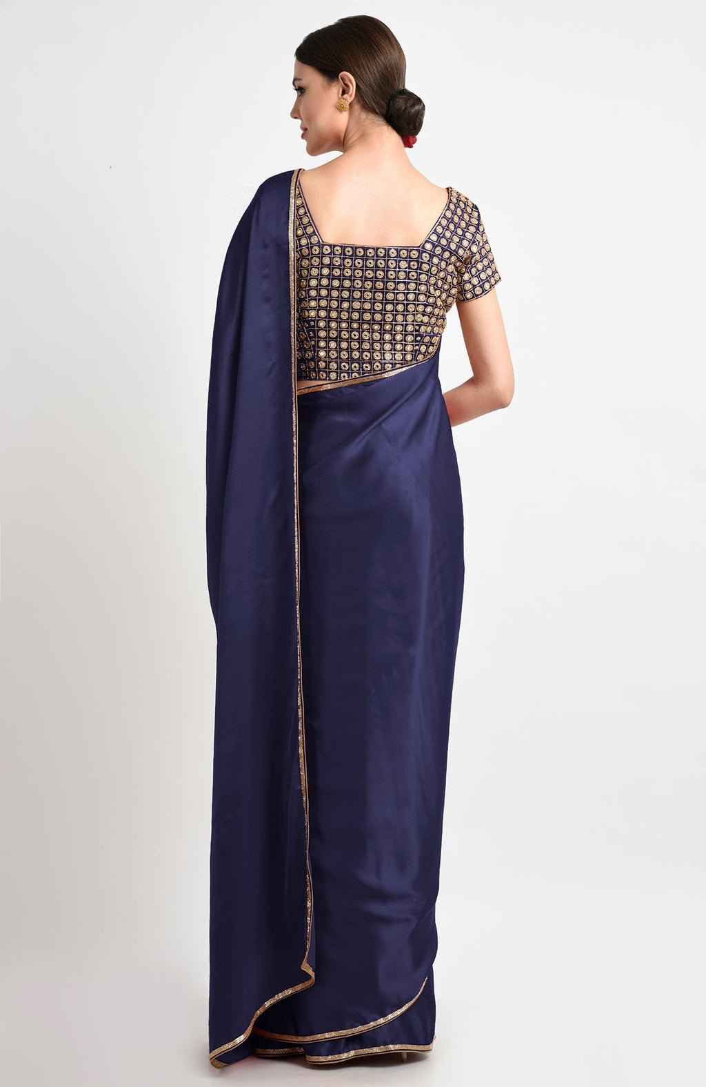 A woman models a midnight blue saree with gold mirror and zardozi embroidery.