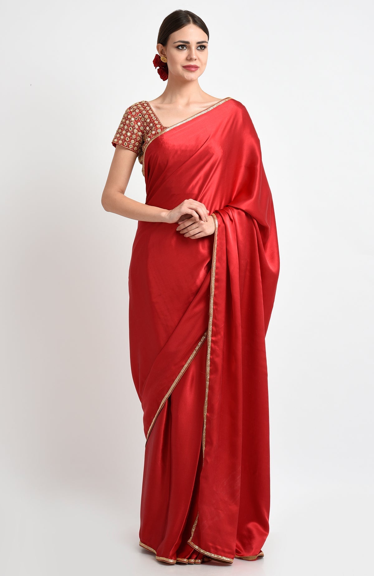 A woman in a red satin silk saree with a gold border and an embroidered blouse.