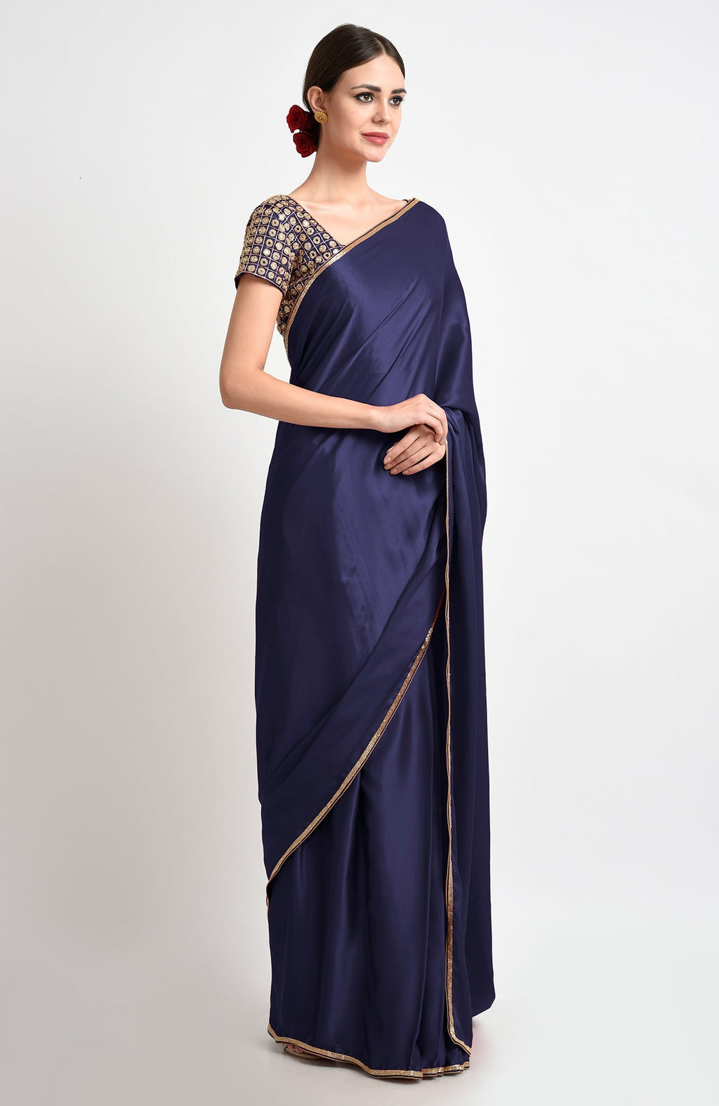 A woman models a midnight blue satin silk saree with gold borders and an embroidered blouse.
