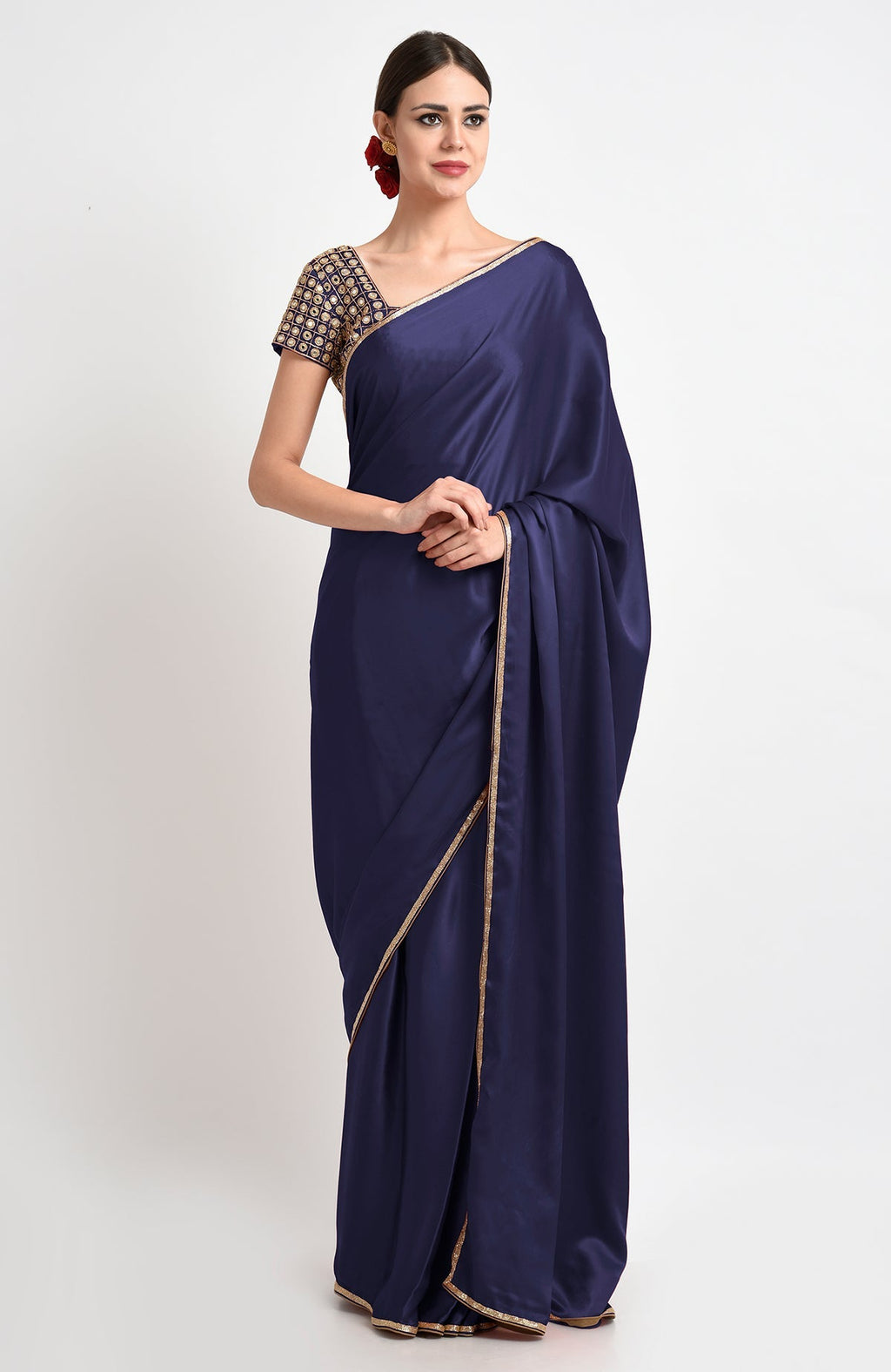 A woman models a midnight blue satin silk saree with gold borders and an embroidered blouse.