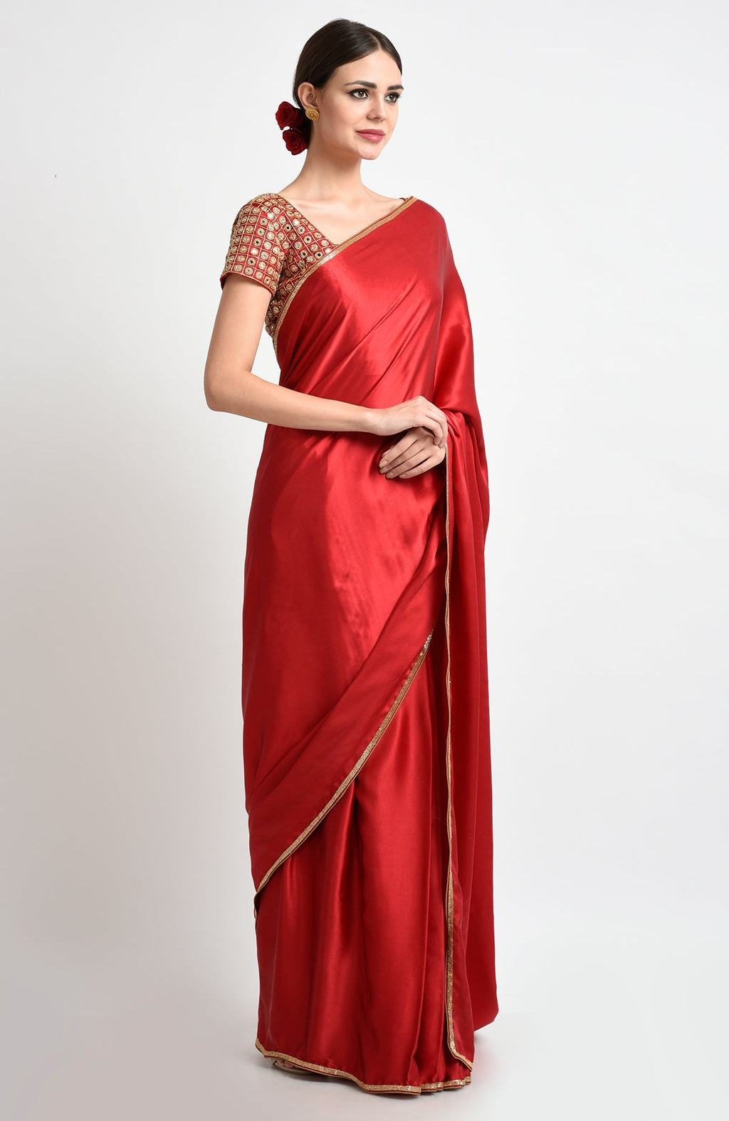 A woman models a royal red satin silk saree with mirror and zardozi embroidery.