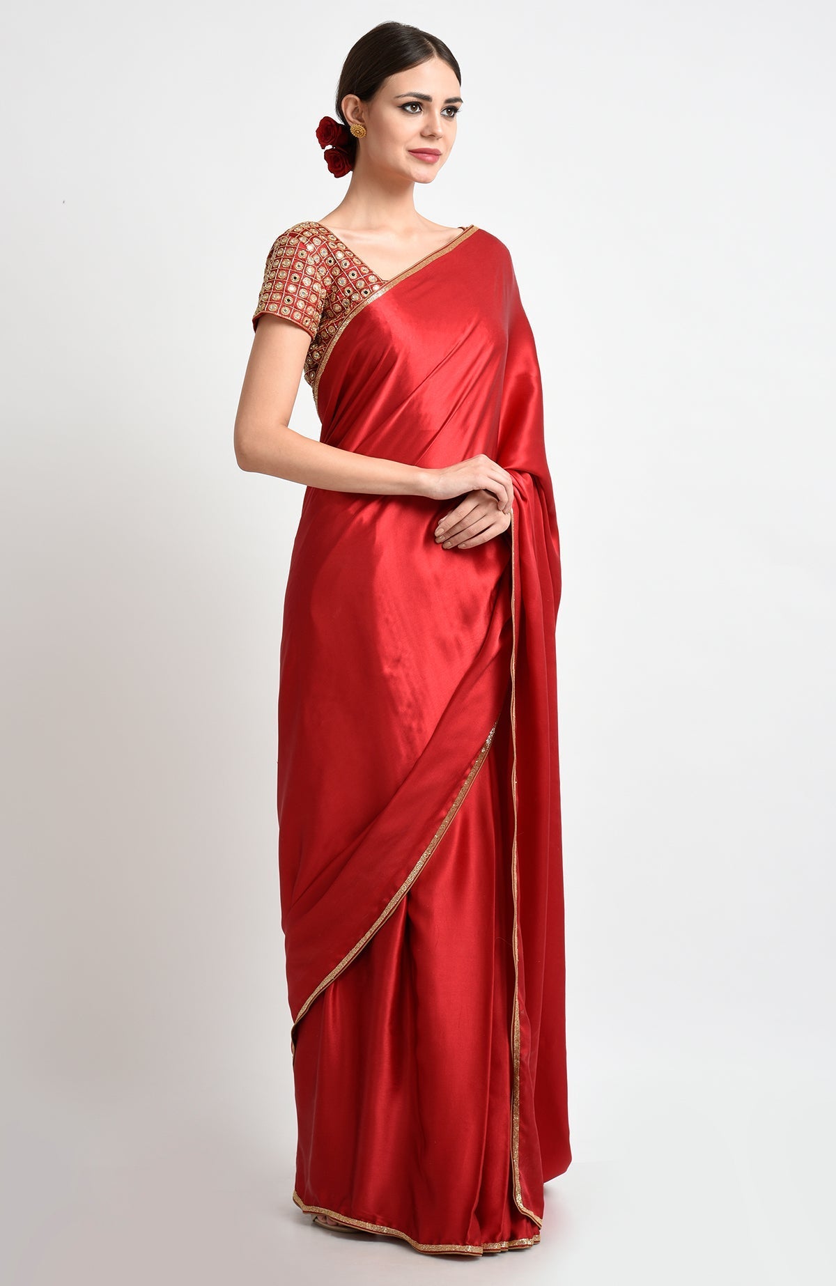 A woman models a royal red satin silk saree with mirror and zardozi embroidery.