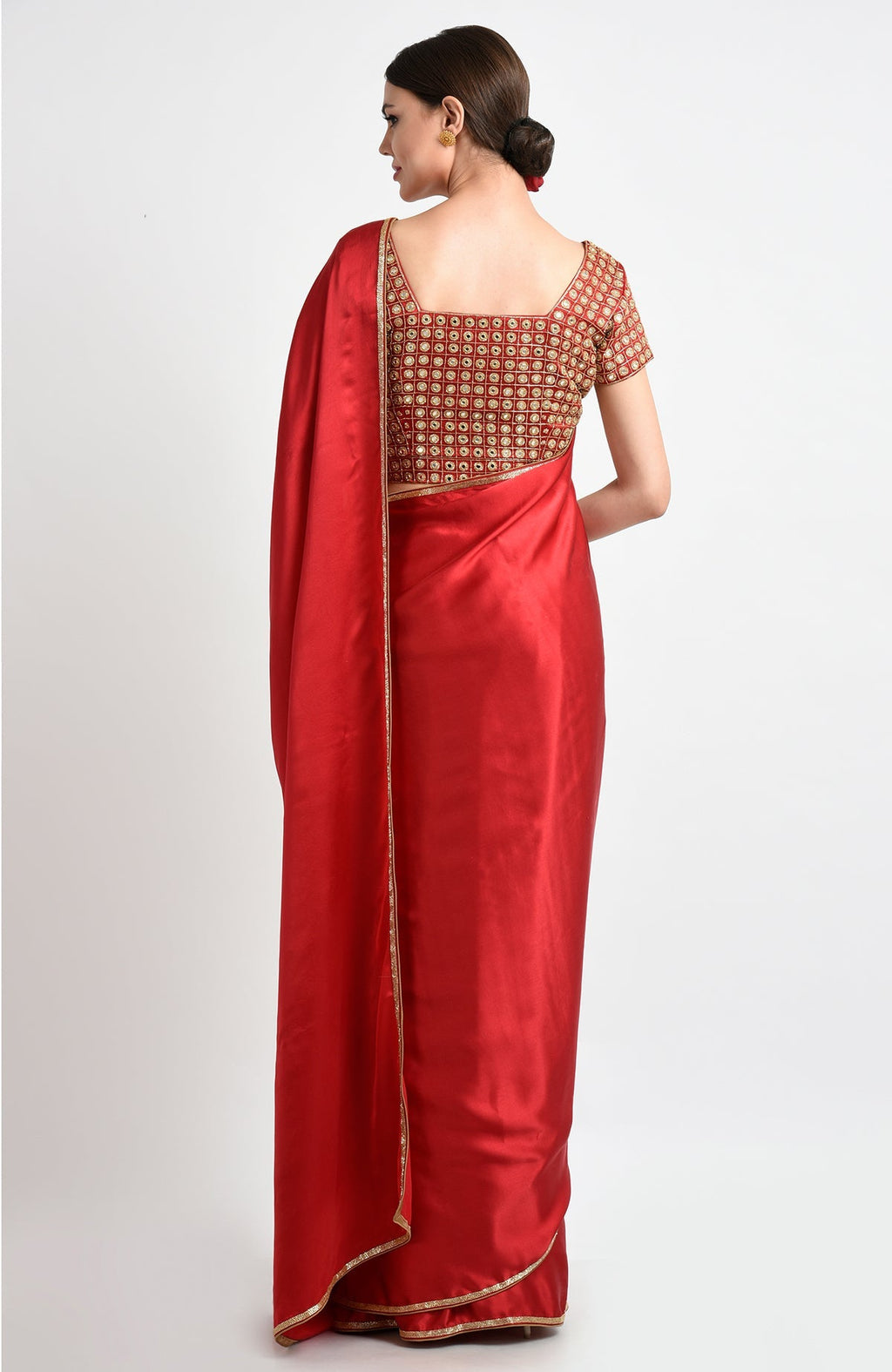 A woman from behind wears a red satin silk saree with mirror and zardozi embroidery.