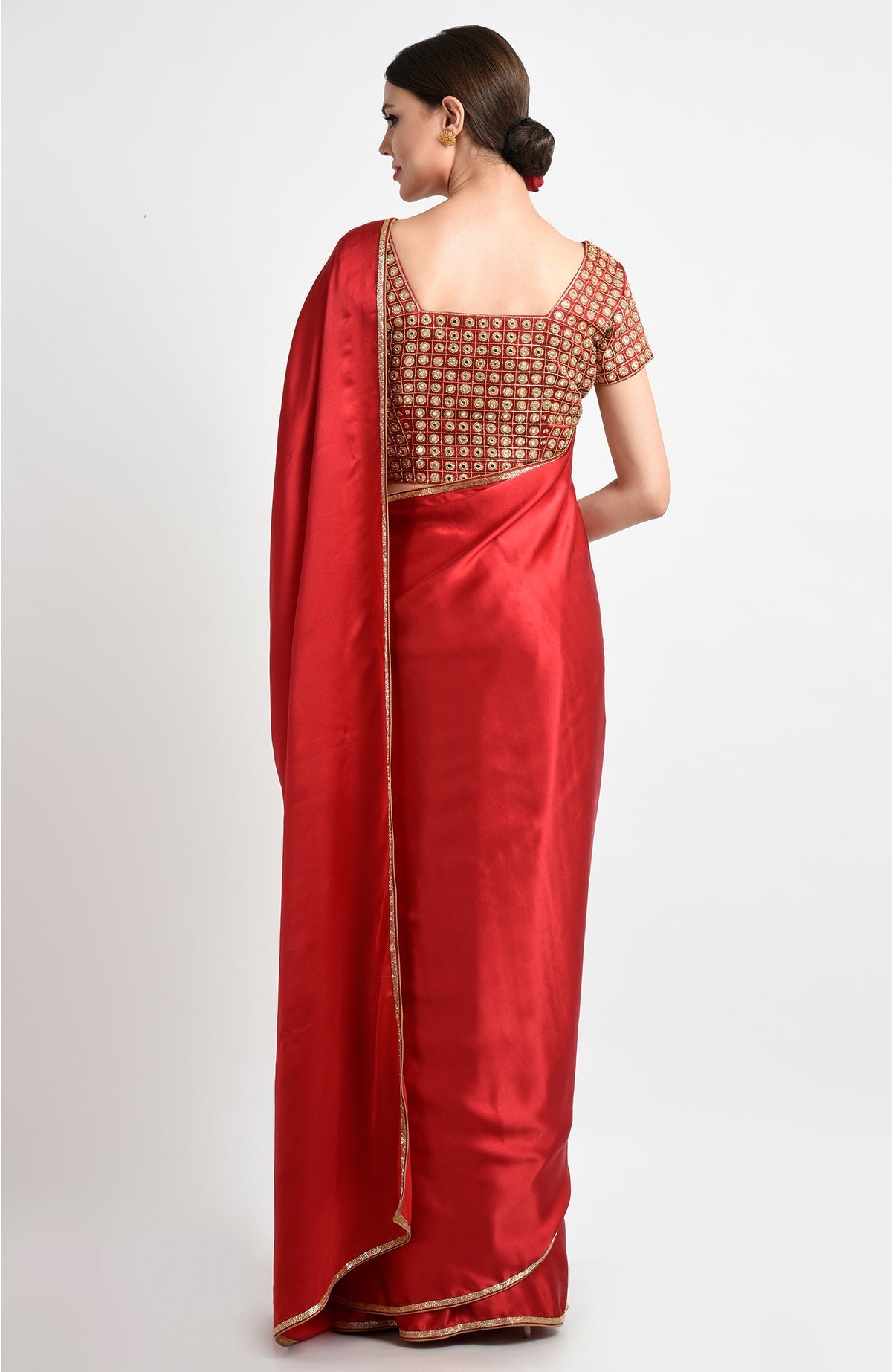 A woman from behind wears a red satin silk saree with mirror and zardozi embroidery.