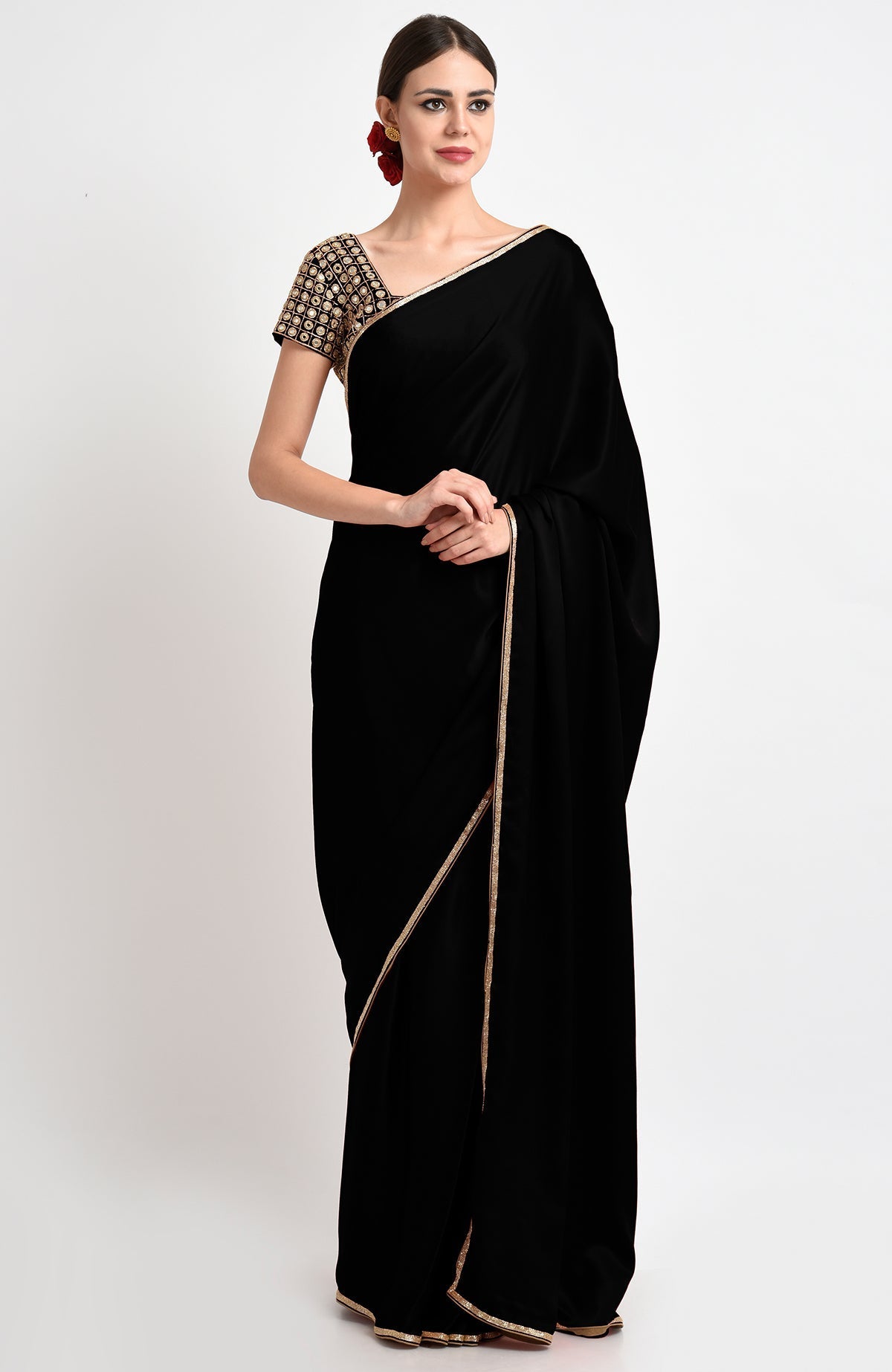 A woman models a black saree with a gold embroidered blouse and trim.