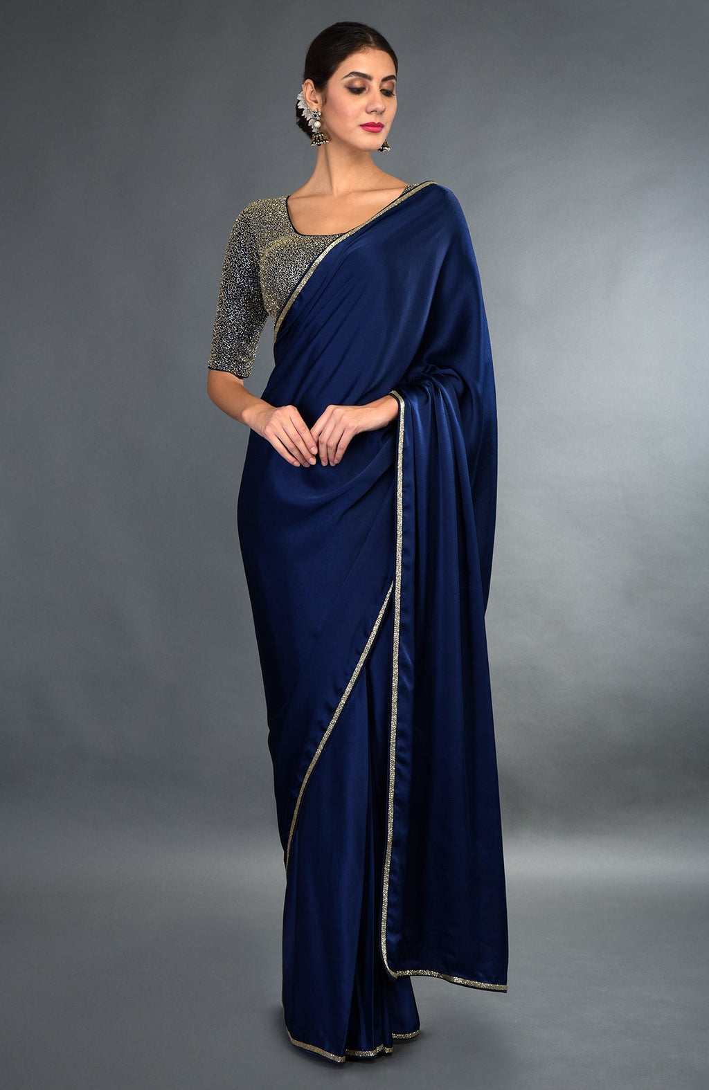 A woman models a midnight blue satin silk saree with gold zardozi borders and a matching blouse.