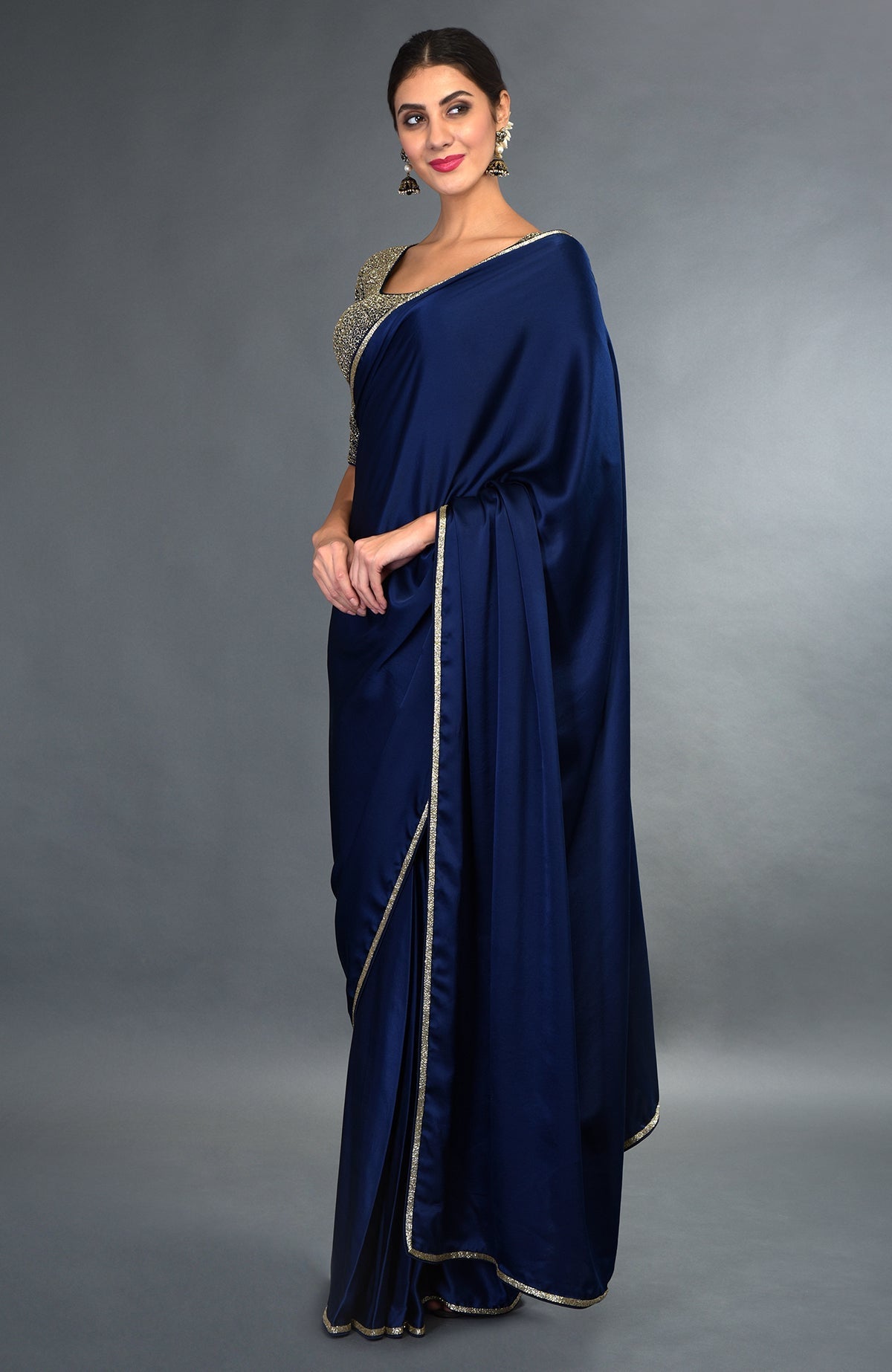 A woman models a midnight blue satin silk saree with gold zardozi borders.