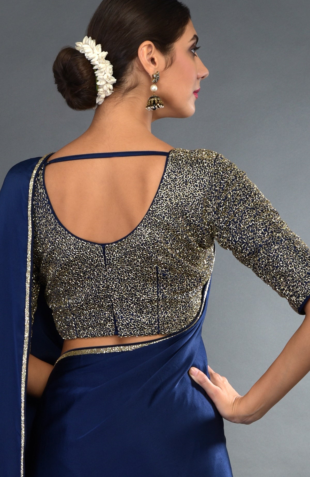 A woman models a midnight blue saree with a gold zardozi embroidered blouse.