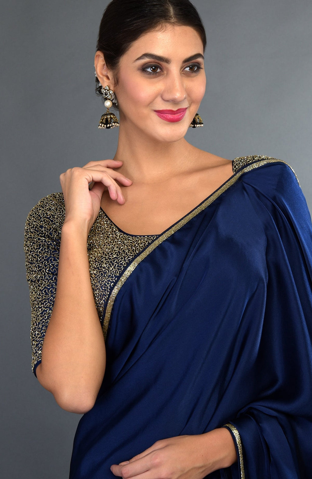 A woman models a midnight blue satin silk saree with gold zardozi embroidery.