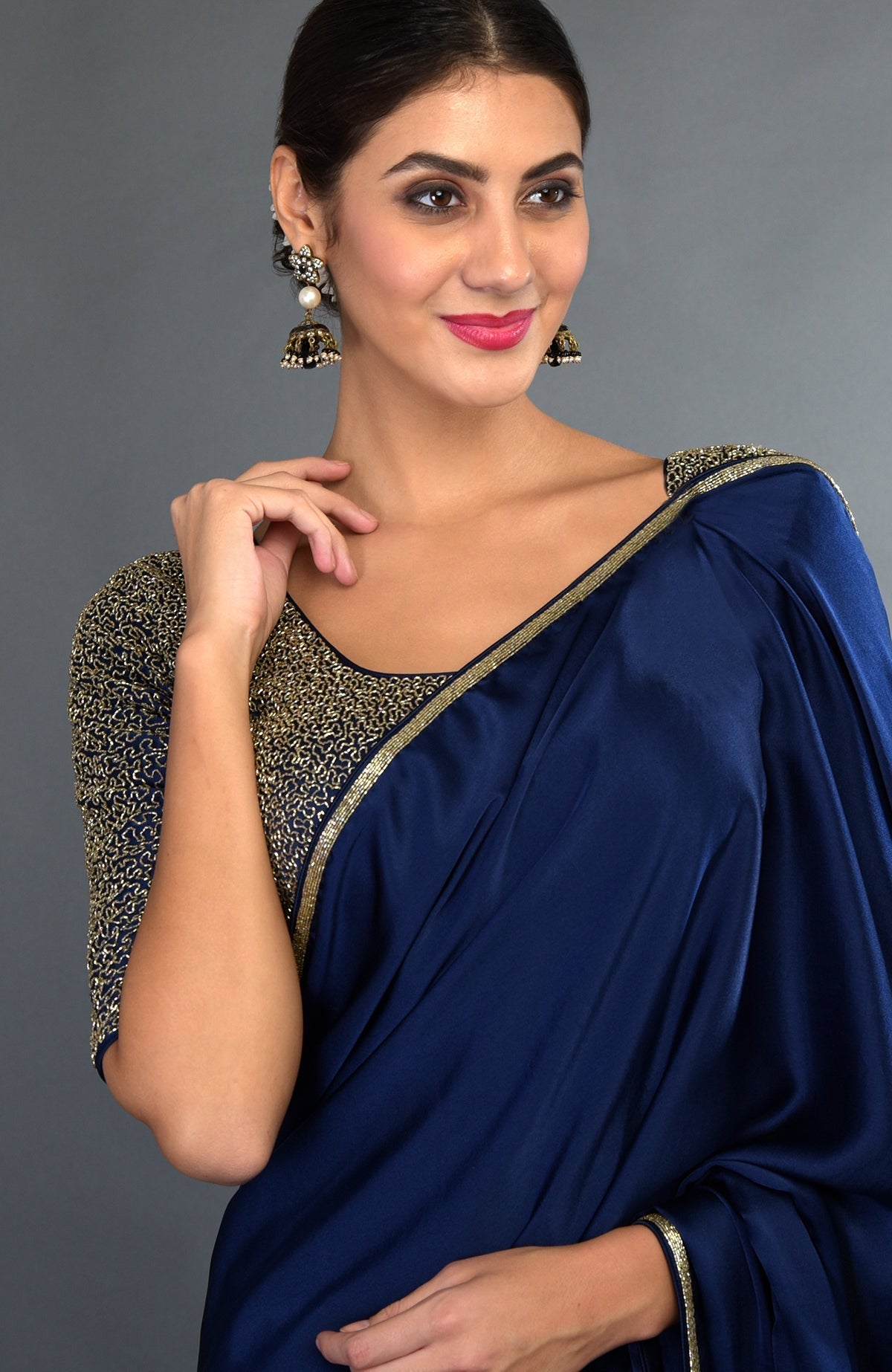 A woman models a midnight blue satin silk saree with gold zardozi embroidery.