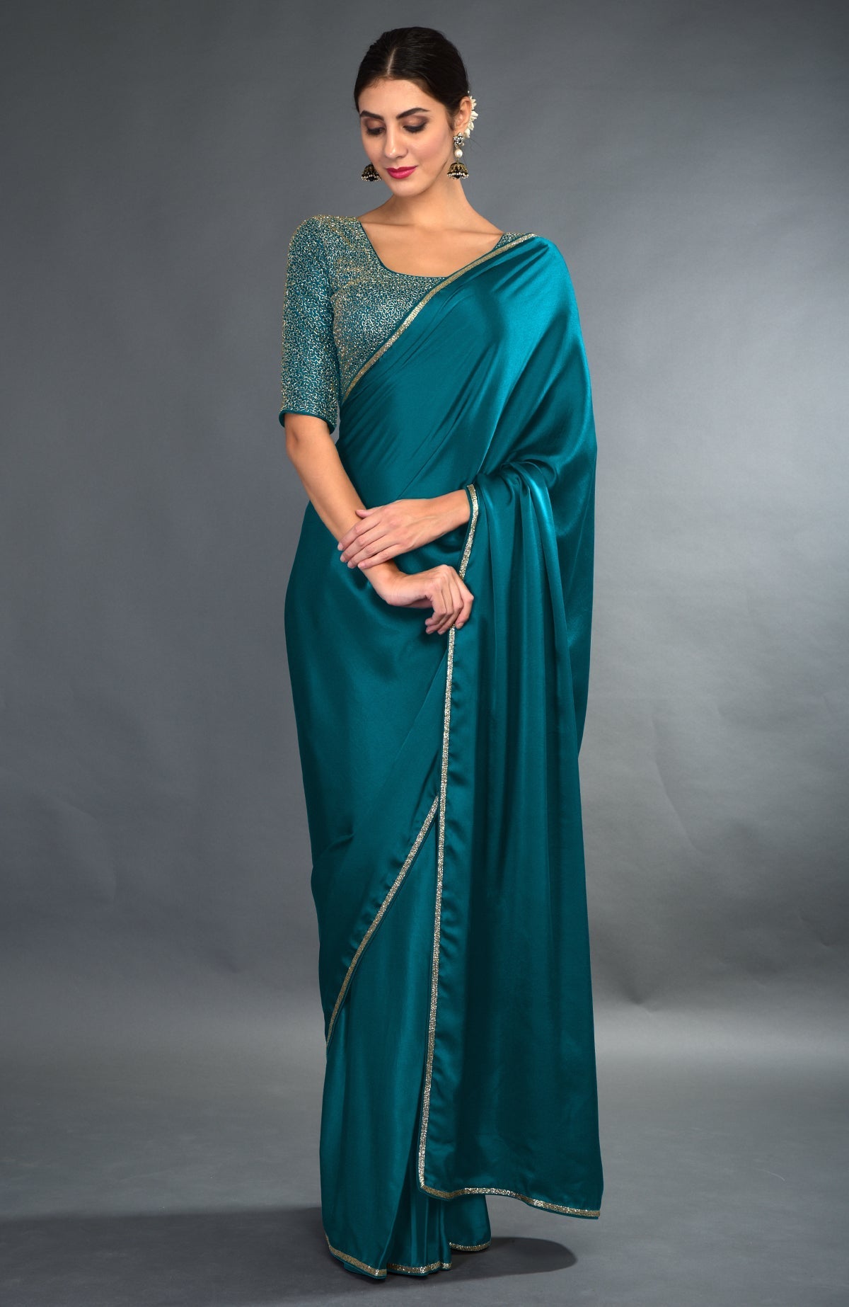 A woman models a midnight blue satin silk saree with gold zardozi embroidery.