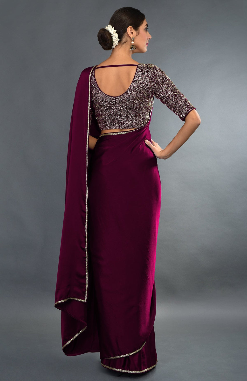 A woman models a burgundy zardozi hand-embroidered saree and blouse from behind.