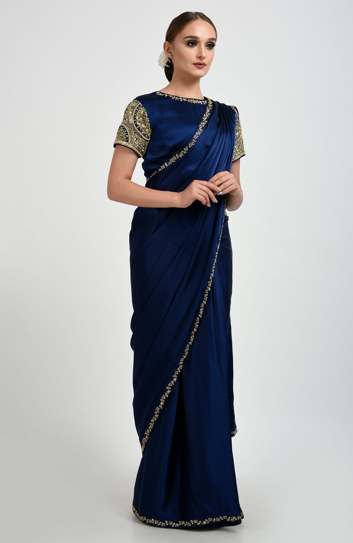 A woman models a sapphire blue saree with zardozi and pearl bead embroidery.