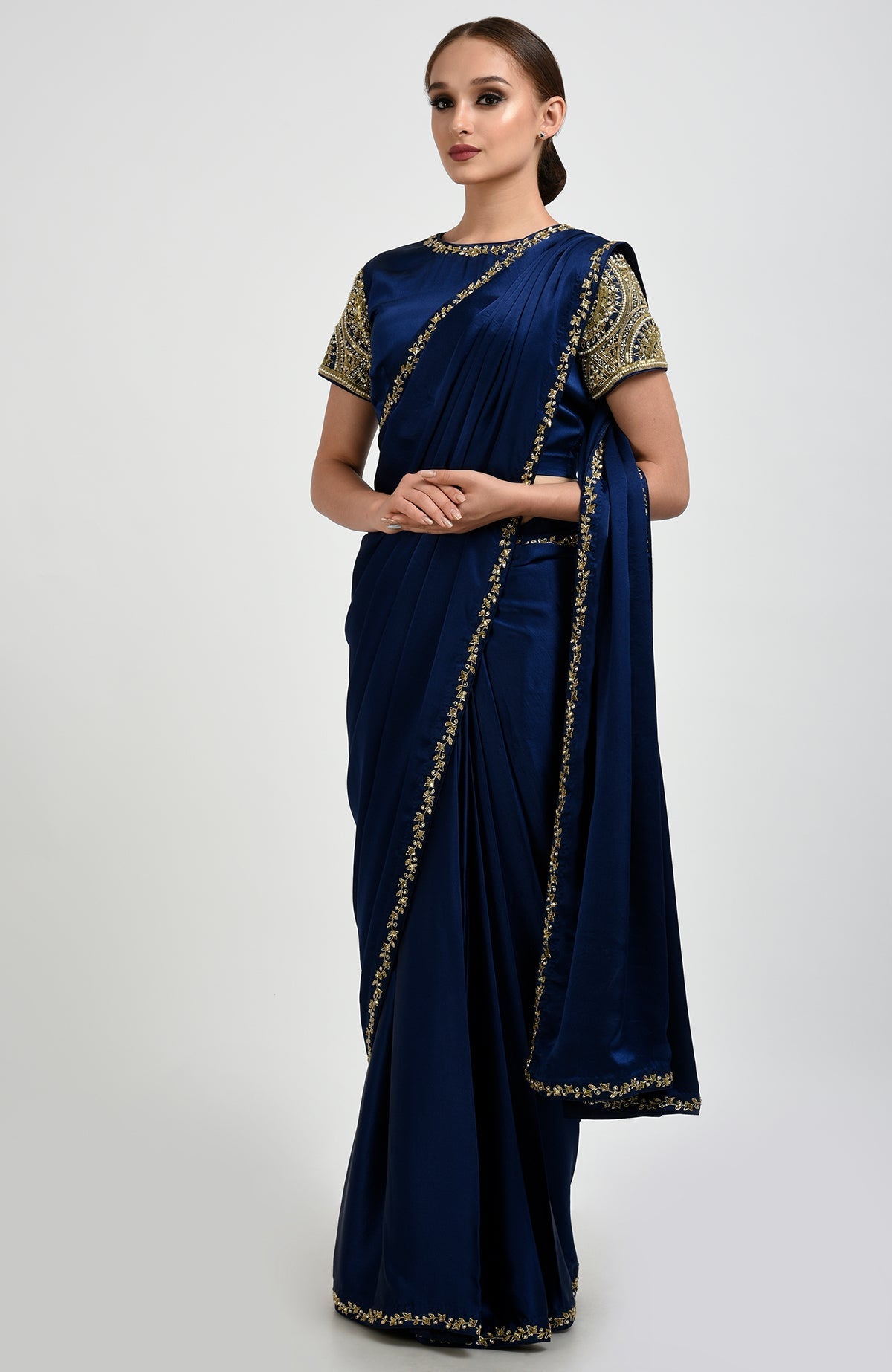 A woman models a sapphire blue satin silk saree with zardozi and pearl embroidery.