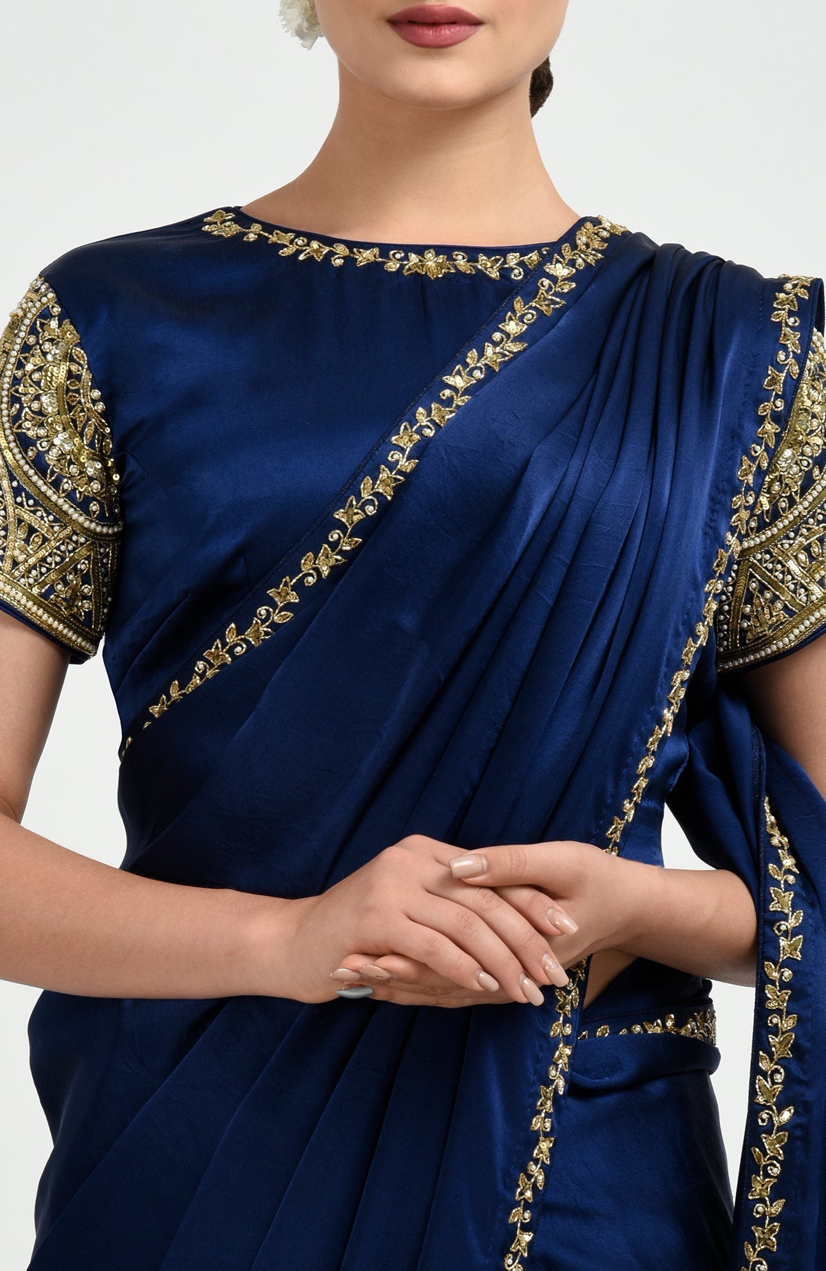 A woman in a sapphire blue saree with gold zardozi and pearl bead embroidery.