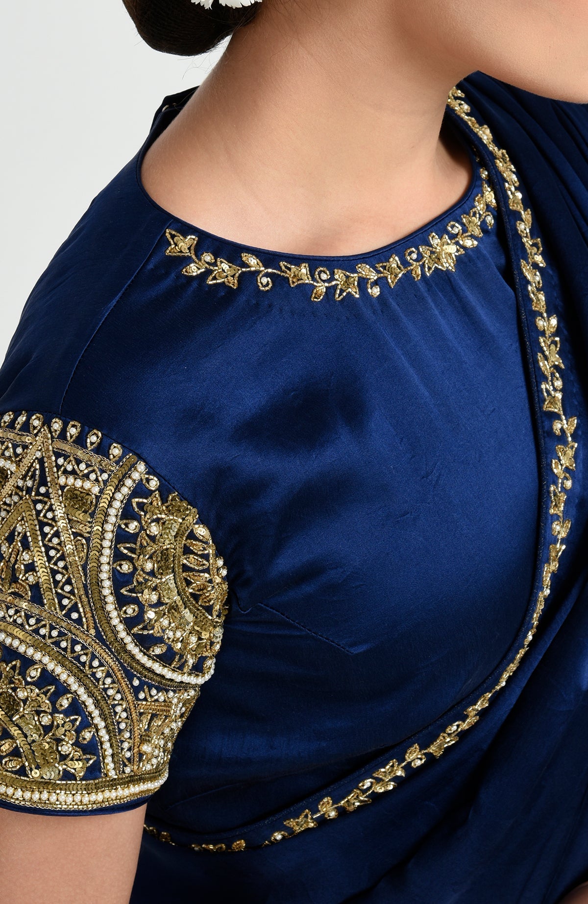A sapphire blue saree with intricate gold zardozi and pearl embroidery on the blouse and border.