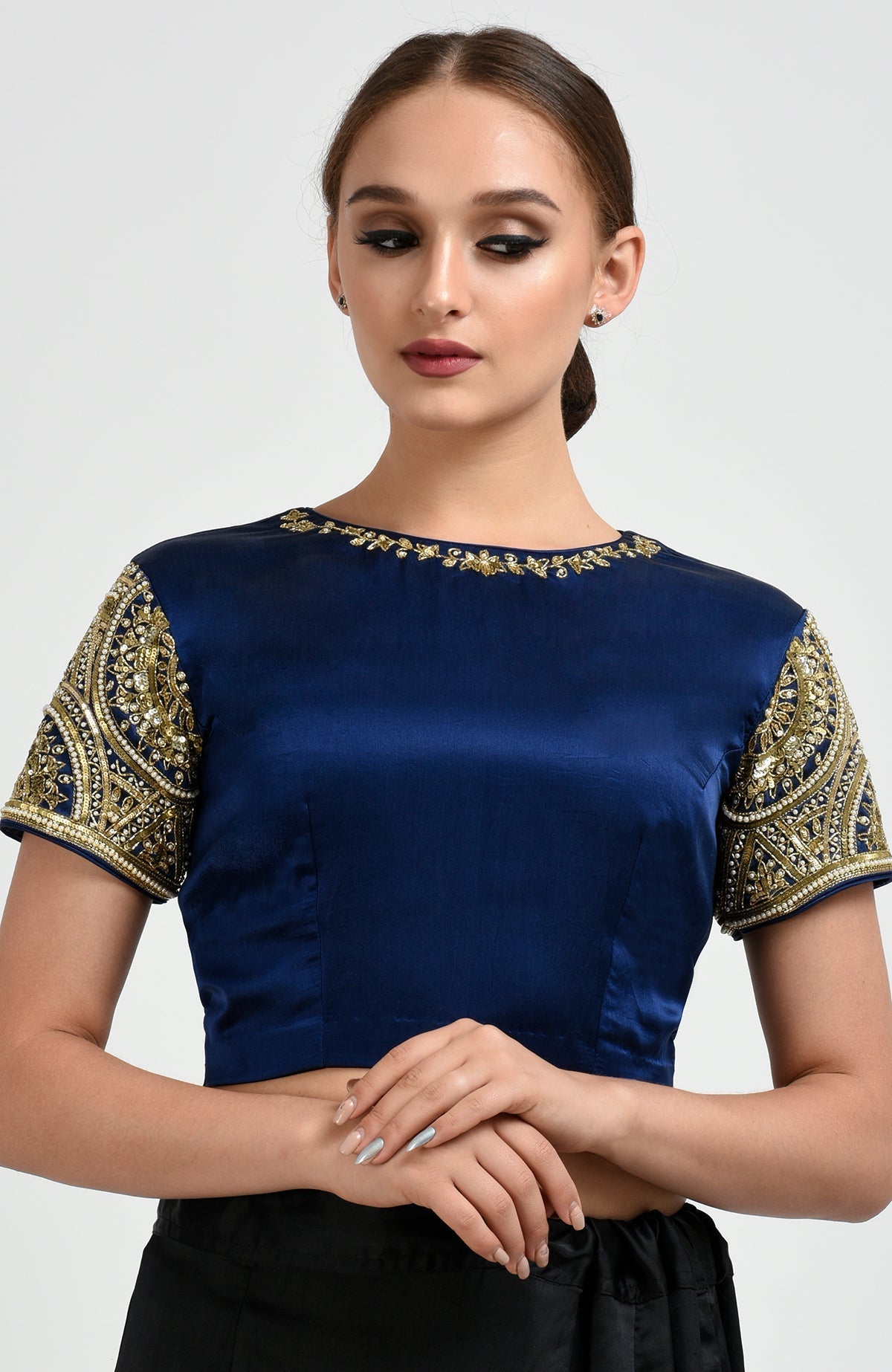 A woman models a sapphire blue satin silk blouse with zardozi and pearl bead embroidery.