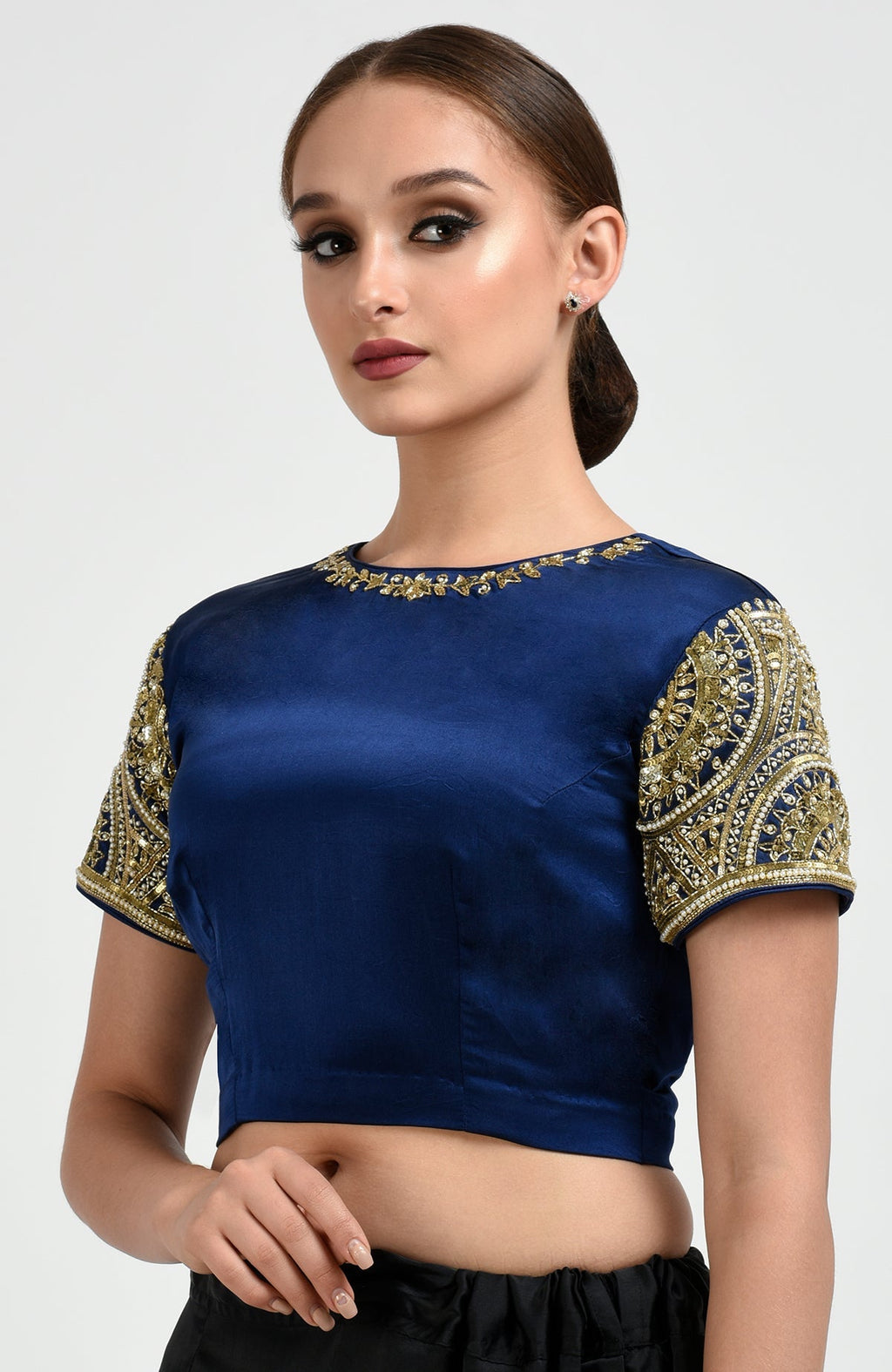 A woman models a sapphire blue blouse with gold zardozi and pearl bead embroidery.