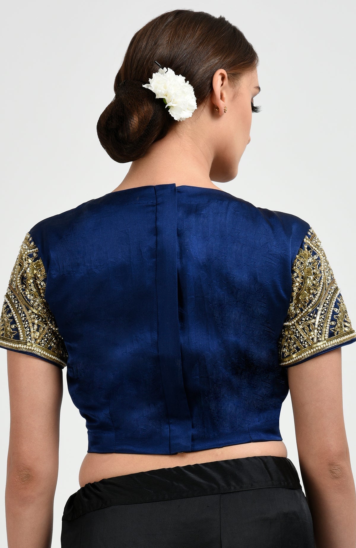 A woman from the back wearing a sapphire blue blouse with embroidered sleeves.