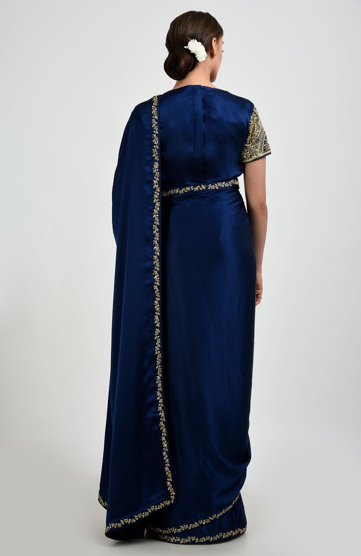 A woman from behind in a sapphire blue saree with gold and pearl embroidery.
