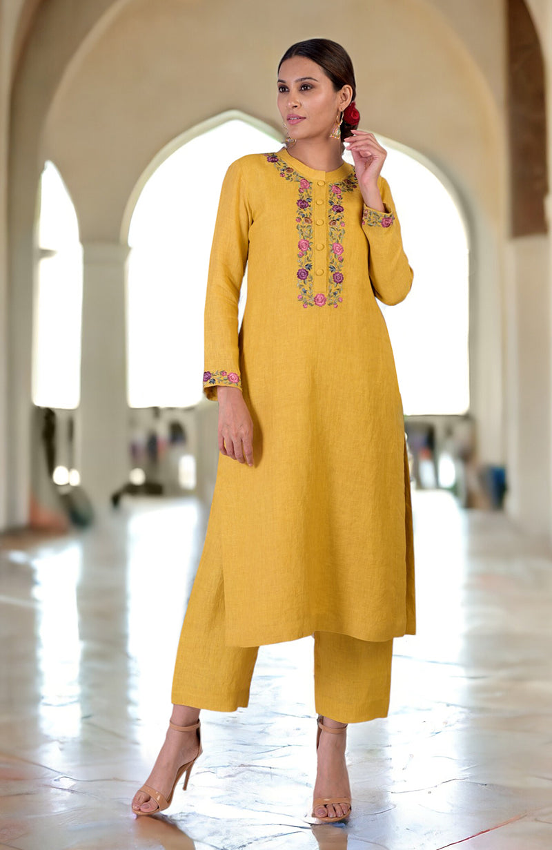A woman models a calendula yellow linen kurta set with Parsi Gara embroidery.