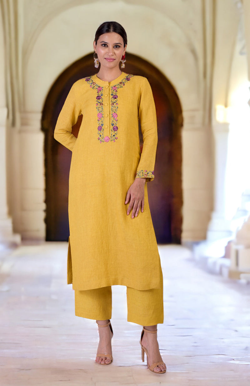 A woman models a calendula yellow linen kurta set with Parsi Gara embroidery.