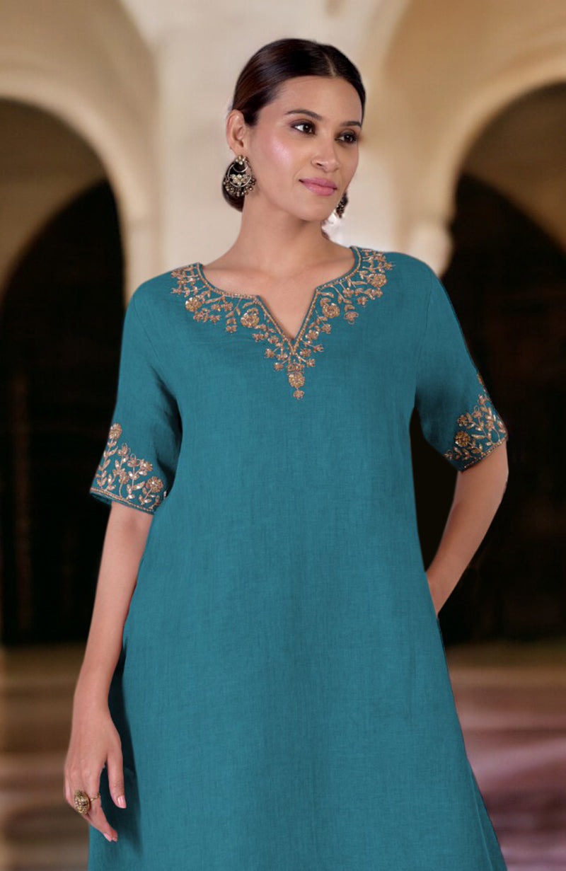 A woman models a mosaic blue linen kurta with gold marori embroidery.
