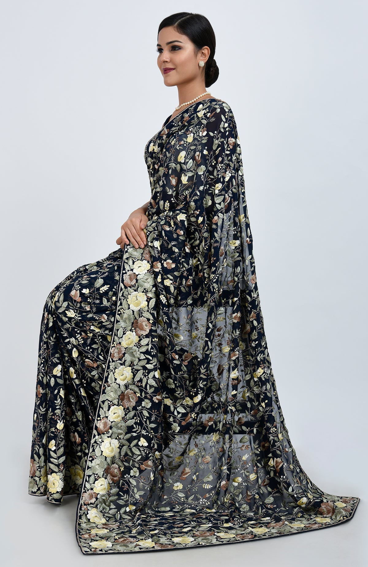 A woman models a midnight blue Parsi Gara hand-embroidered saree with floral patterns.