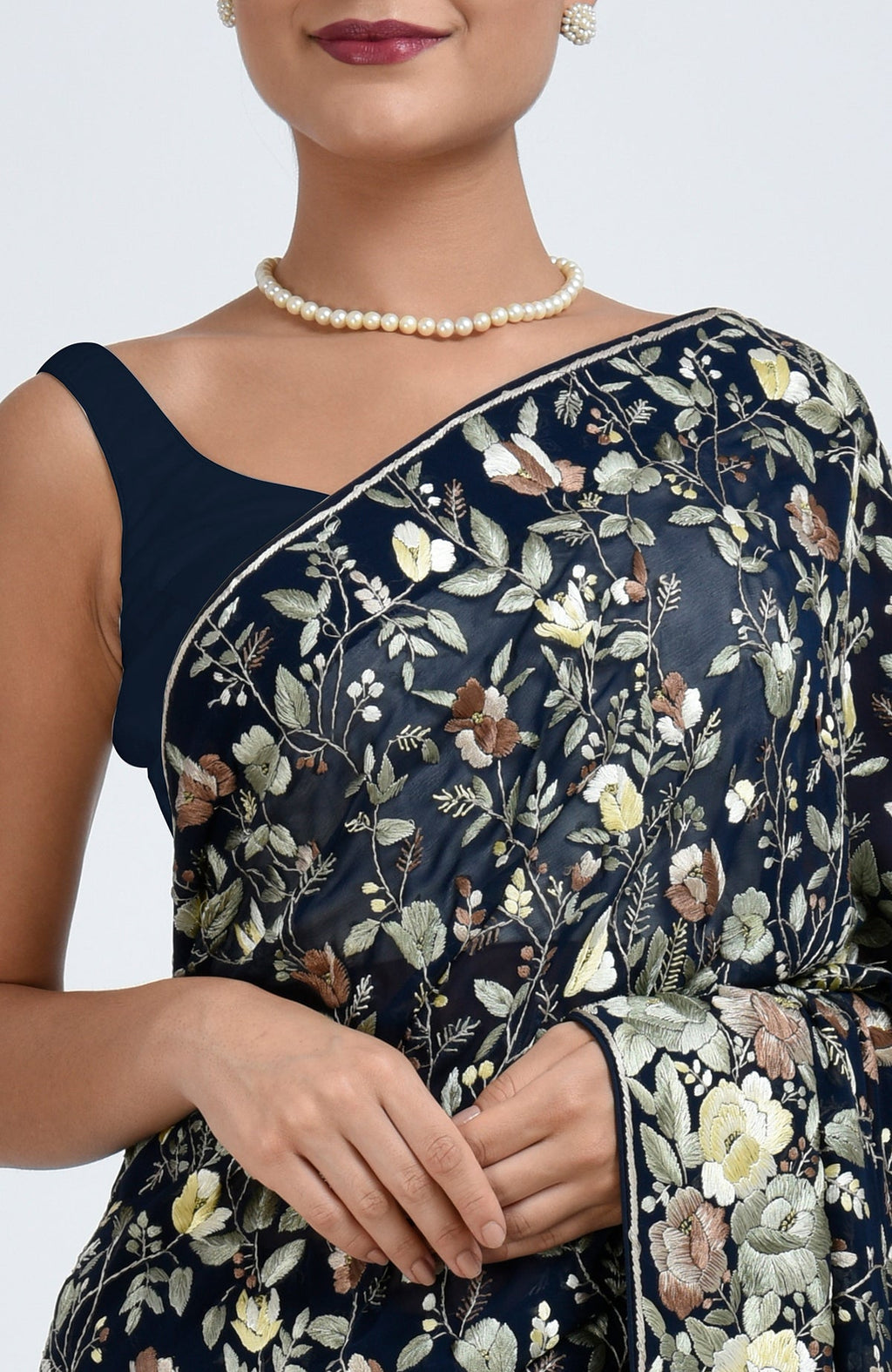 A woman models a midnight blue Parsi Gara hand embroidered saree with a pearl necklace.