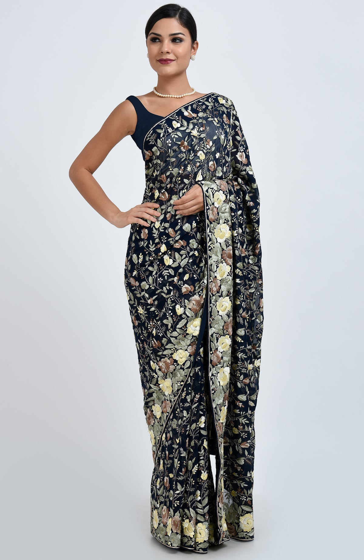 A woman models a midnight blue Parsi Gara hand-embroidered saree with floral patterns.