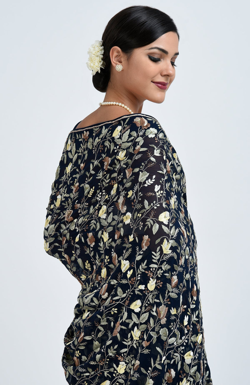 A woman models a midnight blue Parsi Gara hand-embroidered saree with floral patterns.