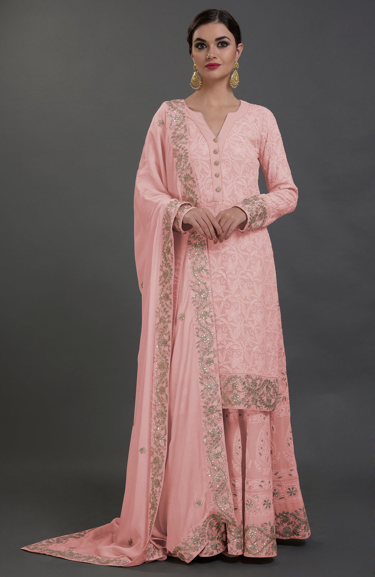 A woman models a pink Chikankari and Gota Patti hand-embroidered sharara suit.