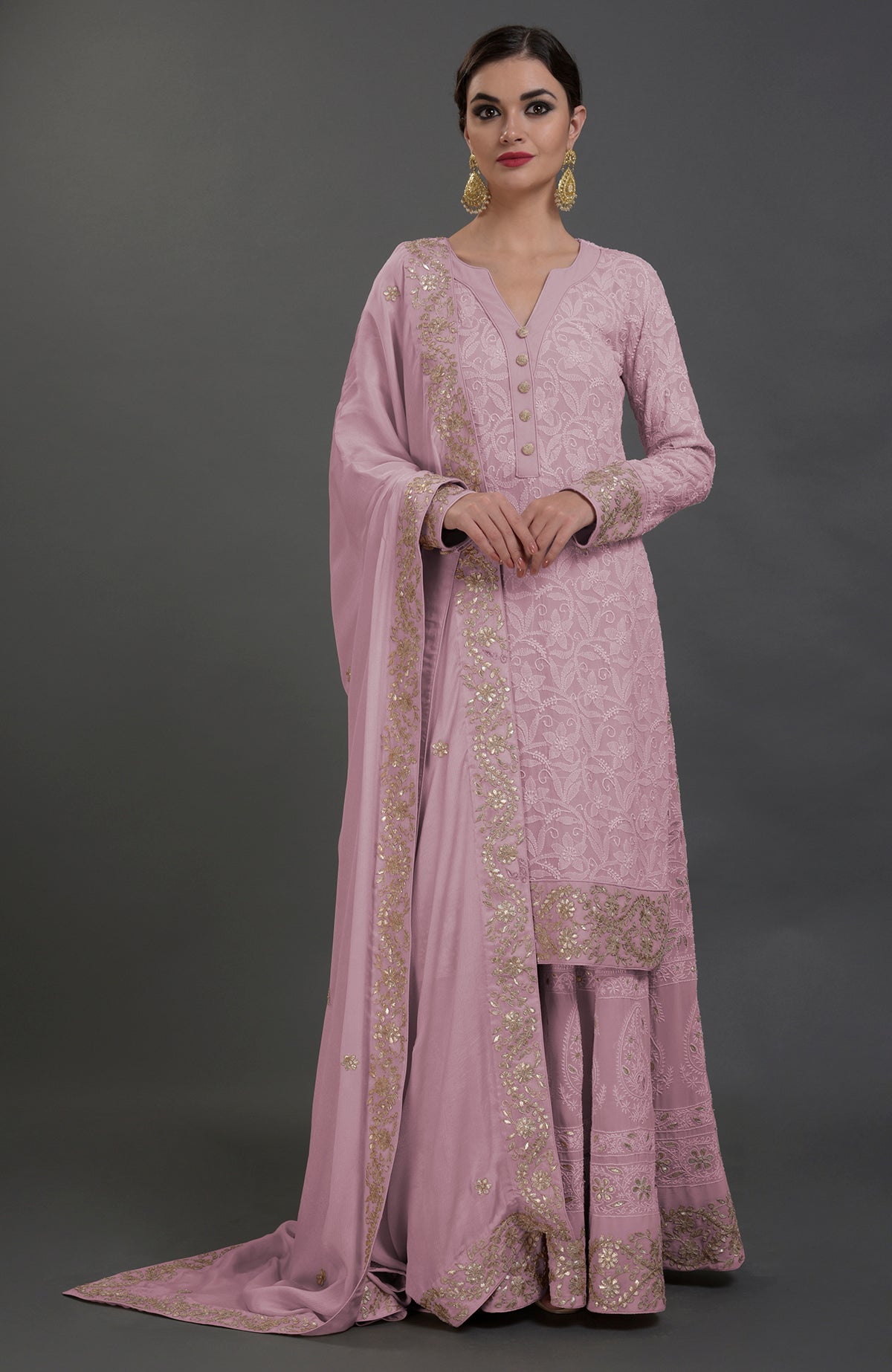 A woman models a pink Chikankari and Gota Patti hand-embroidered sharara suit.