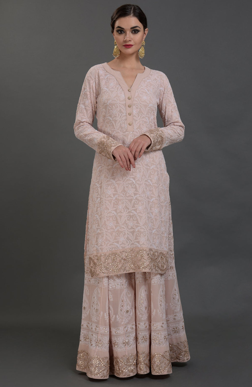 A woman models a pink chikankari and gota patti hand-embroidered sharara suit.