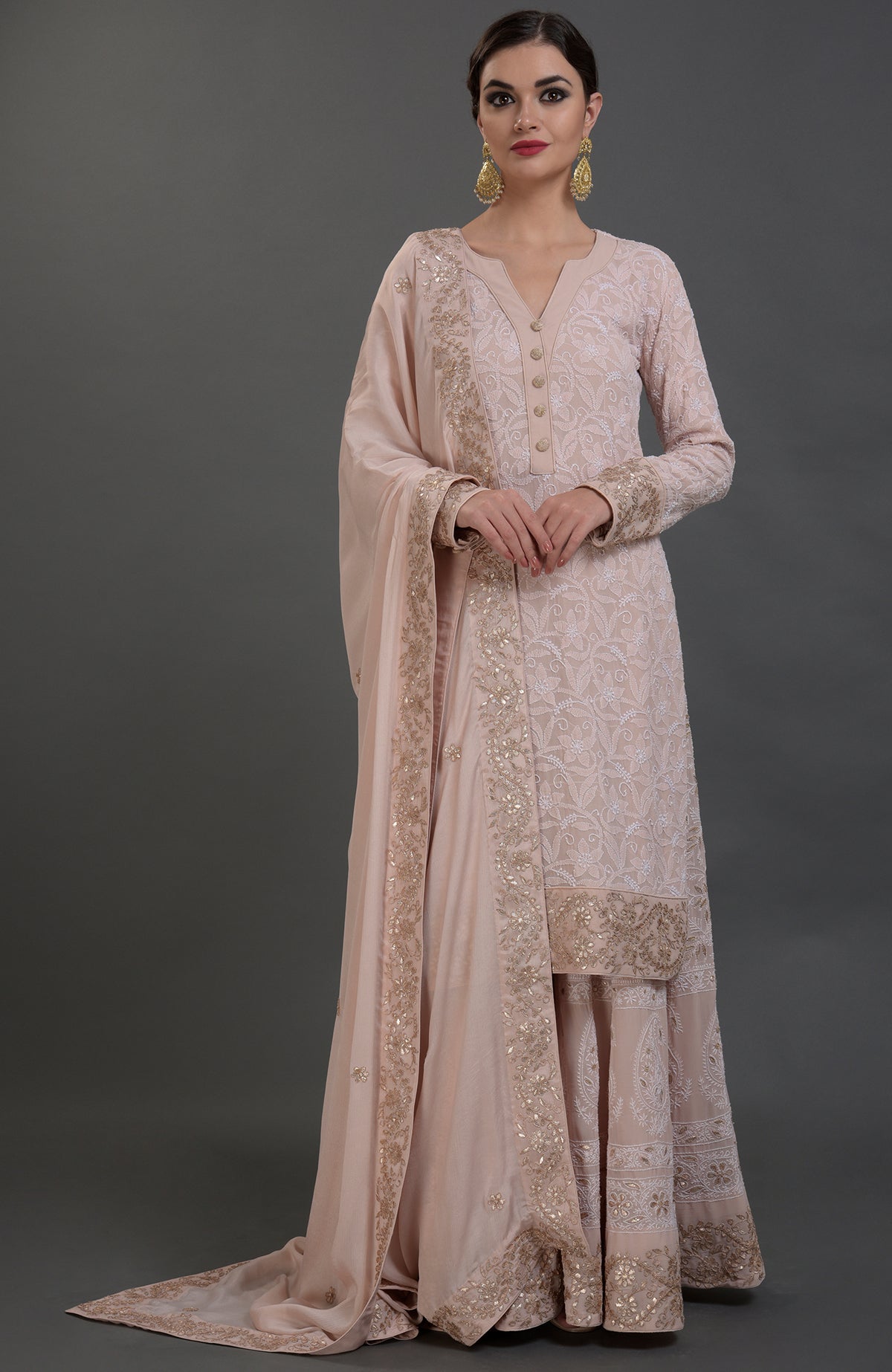 A woman models a pink Chikankari and Gota Patti hand-embroidered sharara suit.