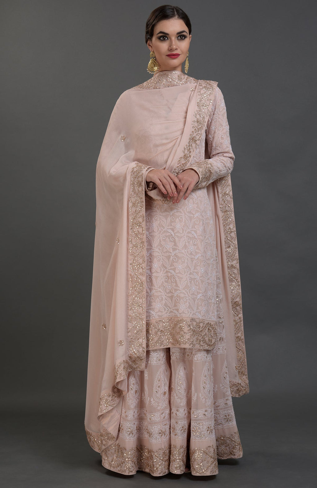 A woman models a pink chikankari and gota patti hand embroidered sharara suit.