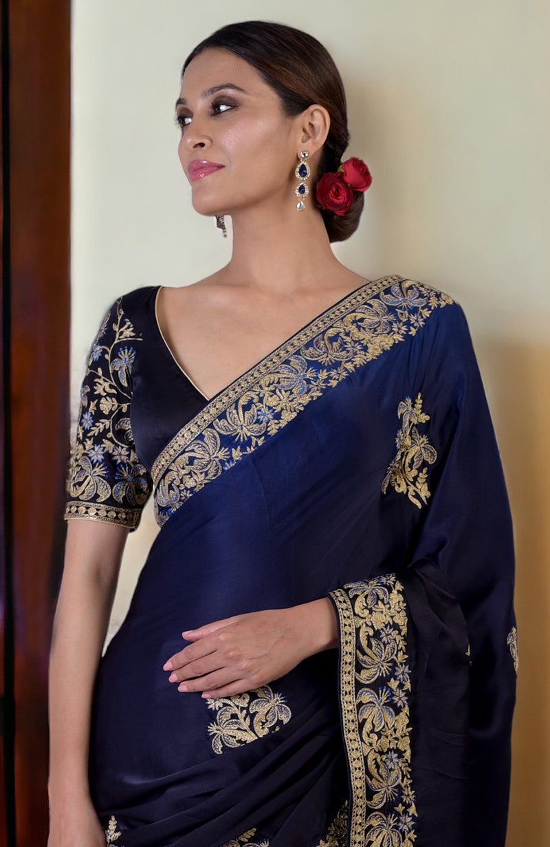 A woman models a midnight blue ombre saree with gold embroidery and a matching blouse.